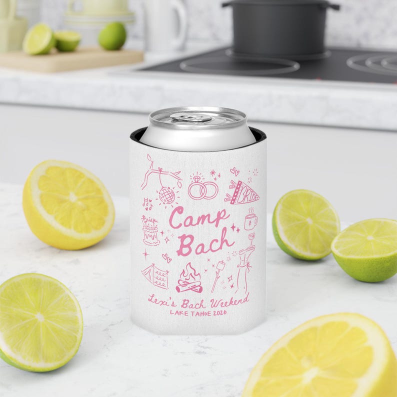 May include: A white can cooler with pink illustrations and text that reads "Camp Bach" and "Lexi's Bach Weekend Lake Tahoe 2020". The cooler is surrounded by cut lemons and limes.