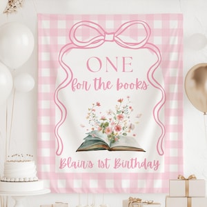 Könnte beinhalten: Ein rosa-weiß karierter Hintergrund mit einem rosa Schleifen- und Banddesign. Der Text "ONE for the books" und "Blair's 1st Birthday" sind abgebildet. Ein offenes Buch mit floralen Akzenten ist zu sehen.