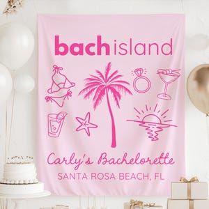 May include: A pink fabric banner with the words "bach island" in a bold, fuchsia font. The banner features illustrations of a bikini, palm tree, ring, cocktail, drink, starfish, and sunset. Text at the bottom reads "Carly's Bachelorette" and "SANTA ROSA BEACH, FL".