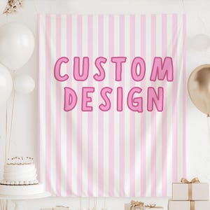 May include: A pink and white striped backdrop with the words "CUSTOM DESIGN" in pink. White and gold balloons are in the background, along with a white cake and wrapped gifts.