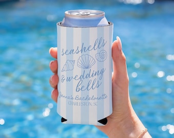 May include: A blue and white striped can cooler with the text "seashells & wedding bells" and seashell illustrations. The text "Jenna's Bachelorette, Charleston, SC" is also printed on the cooler. The cooler is holding a silver can.
