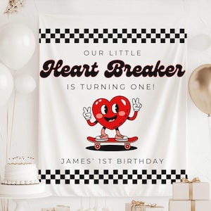Puede incluir: Bandera blanca con bordes a cuadros negros y el texto "OUR LITTLE Heart Breaker IS TURNING ONE!" Un personaje de corazón de dibujos animados en un monopatín está en el centro. El texto "JAMES' 1ST BIRTHAY" está en la parte inferior.