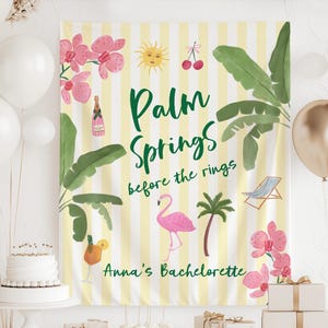 May include: A yellow and white striped banner with the words "Palm Springs before the rings" in green script. The banner features illustrations of a flamingo, palm tree, sun, cherries, and orchids. The text "Anna's Bachelorette" is also included.