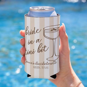 May include: A beige and white striped can cooler with the text "bride in a tini bit" and a martini glass illustration. The text "Jenna's Bachelorette AUSTIN, TEXAS" is also visible. The cooler is holding a silver can.