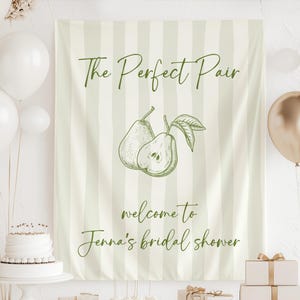 May include: A light green and white striped banner with the text "The Perfect Pair" and "welcome to Jenna's bridal shower". The banner features a sketch of two pears. White and gold balloons and a cake are in the background.