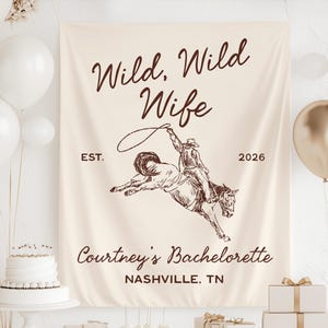 May include: A cream-coloured banner featuring the text "Wild, Wild Wife" and a drawing of a cowboy riding a bucking horse. The banner also includes the text "EST. 2026" and "Courtney's Bachelorette, Nashville, TN".