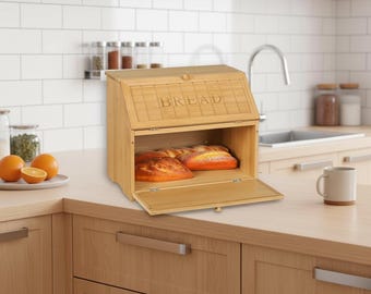 May include: A bamboo bread box with a hinged lid and a lower compartment. The word "BREAD" is etched on the front. The box is open, revealing two loaves of bread. The box is on a wooden countertop.