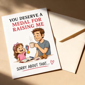 May include: A greeting card with the text "YOU DESERVE A MEDAL FOR RAISING ME" and "SORRY ABOUT THAT..." features an illustration of a father and daughter. The daughter holds a medal, and the father holds a mug. An envelope is next to the card.