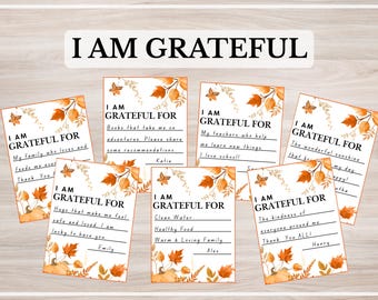 Może przedstawiać: Zestaw kart wdzięczności z napisem "I AM GRATEFUL". Każda karta, ozdobiona jesiennymi liśćmi i motylami, oferuje miejsce na wyrażenie wdzięczności. Tło jest jasne drewniane.