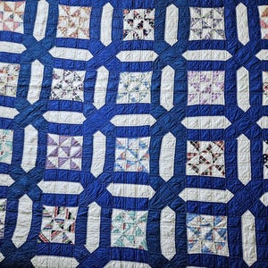 Pode incluir: Um edredom feito à mão com um padrão repetido de quadrados e retângulos. O edredom apresenta um fundo azul escuro com quadrados brancos e estampados em várias cores. O design é um estilo patchwork clássico, perfeito para uma cama ou como decoração de parede.