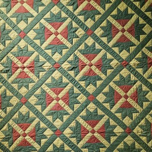 Könnte beinhalten: Ein Steppdecke mit einem sich wiederholenden geometrischen Muster aus sternartigen Formen in Dunkelgrün, gedämpftem Rot mit kleinen weißen Punkten und blassgelbem Stoff. Das Design ist in einem Gitter aus Rauten angeordnet.