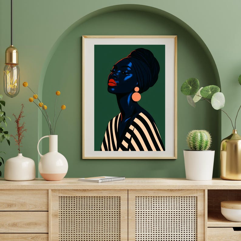 May include: Framed art print featuring a stylized portrait of a person with dark skin, wearing a black head wrap and orange earrings. The person's lips are bright red, and the background is a deep green. The person is wearing a black and white striped top.