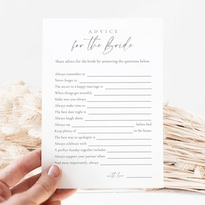 Op de afbeelding: Een witte kaart met de tekst "ADVICE for the Bride" in elegant schrift. De kaart vraagt om advies met invulvragen. De kaart wordt door een hand vastgehouden, met gedroogde bloemenaccenten op de achtergrond.