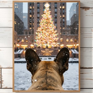 May include: A framed photograph featuring a dog looking at a brightly lit Christmas tree in a snowy urban setting. The dog's ears and the back of its head are visible in the foreground, with the tree and buildings in the background.