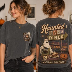 May include: A charcoal gray short-sleeve t-shirt featuring a small graphic on the front left chest and a large graphic on the back. The designs depict a ghost wearing a hat, holding a coffee pot, and serving a slice of pie at a diner.