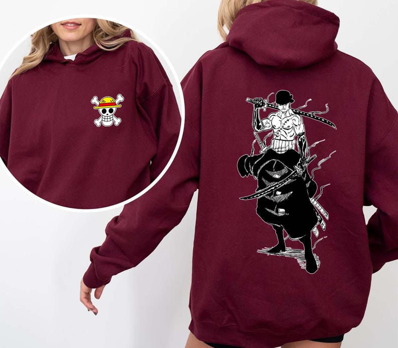 K&ouml;nnte beinhalten: Burgunderfarbener Kapuzenpullover mit einem kleinen Totenkopf- und gekreuzten Knochen-Logo auf der Vorderseite und einer gro&szlig;en Schwarz-Wei&szlig;-Illustration eines Schwertk&auml;mpfers auf der R&uuml;ckseite. Der Hoodie hat eine Kapuze und lange &Auml;rmel.