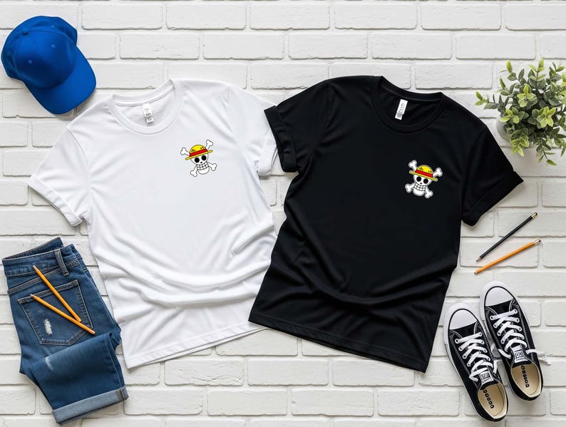 K&ouml;nnte beinhalten: Zwei T-Shirts, eines wei&szlig; und eines schwarz, jeweils mit einer kleinen Grafik eines Sch&auml;dels und gekreuzten Knochen mit einem Strohhut. Die Shirts sind mit einer blauen Baseballkappe, Jeans, Bleistiften und schwarz-wei&szlig;en Turnschuhen ausgelegt.