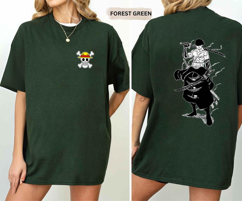 K&ouml;nnte beinhalten: Forstgr&uuml;nes T-Shirt mit einem kleinen Cartoon-Sch&auml;del- und gekreuzten Knochen-Logo auf der Vorderseite. Die R&uuml;ckseite des T-Shirts zeigt eine schwarz-wei&szlig;e Grafik einer Figur mit Schwertern. Das T-Shirt hat eine lockere Passform.