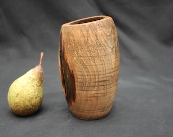 May include: A handcrafted wooden vase with a natural finish, featuring a slightly angled opening. A ripe pear with a green and yellow skin sits beside the vase. The vase is approximately 15 cm tall.