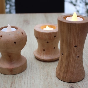 Peut inclure: Trois bougeoirs en bois avec des bougies LED. Les bougeoirs sont en bois brun clair et ont des formes variées. Les bougeoirs sont posés sur une surface en bois brun clair.