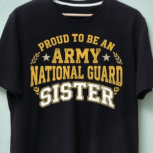 May include: Black t-shirt with the text "PROUD TO BE AN ARMY NATIONAL GUARD SISTER" in yellow and white lettering. The design includes stars and laurel leaf accents, creating a patriotic theme.