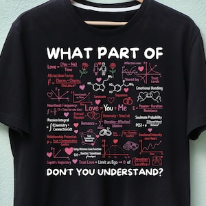 May include: Black t-shirt with white and pink graphics. The design includes equations and diagrams about love, with the text "WHAT PART OF DON'T YOU UNDERSTAND?" in white. Features hearts and romantic symbols.