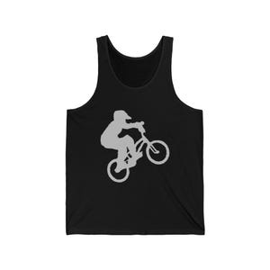 Op de afbeelding: Zwart mouwloos shirt met een grijs silhouet van een BMX-fietser die een truc uitvoert. De afbeelding toont de fietser in de lucht op zijn fiets. De tanktop heeft een ronde hals en is gemaakt van een zacht materiaal.