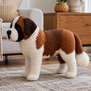 May include: A crochet stuffed animal shaped like a Saint Bernard dog. The figure features a white chest and legs, brown patches on the back and ears, and a black and white face with a dark nose and eyes. The tail ends in a white tuft of yarn.