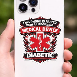 May include: A white smartphone with a sticker that reads "THIS PHONE IS PAIRED WITH A LIFE-SAVING MEDICAL DEVICE". The sticker features a red medical symbol and the word "DIABETIC".