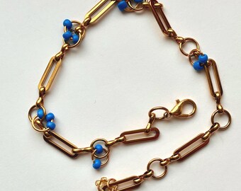 Bracelet goldplated stainless steel with bright blue pearls of glass.