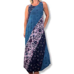 May include: A sleeveless maxi dress featuring a diagonal color-blocked design. The garment combines panels of deep blue with intricate geometric patterns, a light lavender section with dark floral prints, and a solid dark navy floral panel.