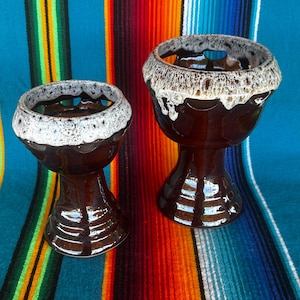 May include: A set of three ceramic mugs with a speckled, matte finish. The mugs are in shades of cream, light gray, and dark gray. Each mug has a simple, modern design and a rounded handle. The mugs are stacked on top of each other.