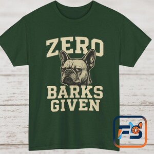 Peut inclure: T-shirt vert foncé avec l'inscription "ZERO BARKS GIVEN" dans une police vintage. Le design comprend une illustration détaillée du visage d'un bouledogue français. Le texte et l'illustration sont de couleur crème, contrastant avec le vert foncé du t-shirt.