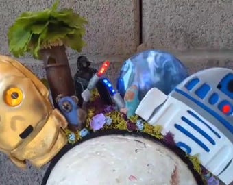 C-3POとR2-D2が戦場にいる様子、エンドアが光る様子、そしてダース・ベイダーがイウォークとライトセーバーで戦っている様子が描かれた、光るスター・ウォーズのカスタムイヤーカチューシャ。
