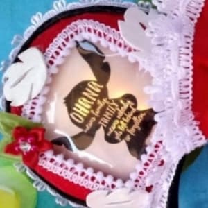 K&ouml;nnte beinhalten: Ein rotes Stirnband mit wei&szlig;er Spitzenborte, wei&szlig;en blattf&ouml;rmigen Akzenten und einer kleinen roten Blume mit einem zentralen Kristall. In der Mitte befindet sich eine kreisf&ouml;rmige Grafik mit dem Text OHANA means family, means nobody gets left behind or forgotten.