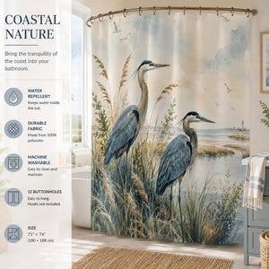May include: A shower curtain featuring a watercolour illustration of two blue herons standing in tall coastal grasses near a body of water. The design includes flying birds and a distant lighthouse. It measures 180 cm by 188 cm.