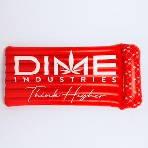 May include: A rectangular red inflatable pool float with a white leaf graphic and the text DIME INDUSTRIES Think Higher printed in white. The right side features a raised pillow section with a repeating white logo pattern on the red surface.