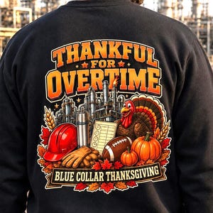 May include: A black sweatshirt featuring a graphic print with the text THANKFUL FOR OVERTIME and BLUE COLLAR THANKSGIVING. The design includes a red hard hat, work gloves, a thermos, a clipboard, a football, pumpkins, and a turkey.