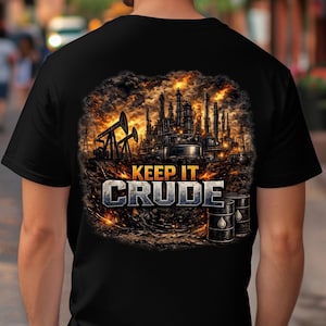 May include: Black t-shirt featuring an industrial graphic with oil derricks and refinery structures. The text "KEEP IT CRUDE" is displayed in a metallic font. The shirt is worn by a person in an outdoor setting.