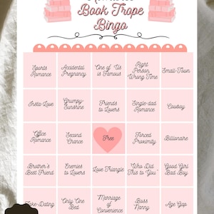 Puede incluir: Una tarjeta de juego de Bingo de Romance Book Trope rosa y blanca con varios temas de novelas románticas. La tarjeta incluye el texto "Romance Book Trope Bingo" y "Instant Download".