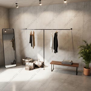 Puede incluir: Una moderna exhibición de ropa con una barra de metal negro con prendas colgadas. También hay un espejo de cuerpo entero, un banco y equipaje. La habitación tiene un diseño minimalista con tonos neutros y una planta en maceta.