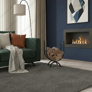 Könnte beinhalten: Ein modernes Wohnzimmer mit einem dunkelgrünen Sofa, einem grauen Teppich und einer schwarzen Bogen-Stehleuchte. Ein dekorativer Metall-Holzhalter ist mit Brennholz gefüllt. Ein Kamin mit Flammen befindet sich an der Wand.