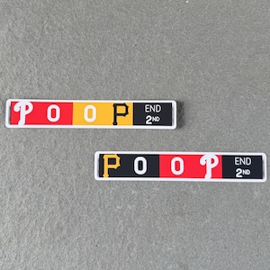 以下が含まれることがあります： 白い文字で「POOP」と書かれた2つの長方形ステッカー。ステッカーは、赤、黄、黒のセクションを持つカラーブロックデザインです。「END 2ND」の文字も表示されています。