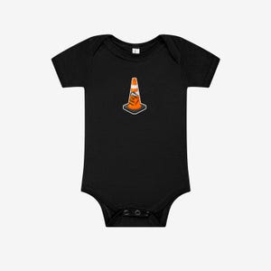 May include: A black short-sleeved baby bodysuit featuring a centered graphic of an orange traffic cone with a white reflective stripe. The cone has the text "HOIST THE CONE" printed in black letters on its side, set against a dark background.