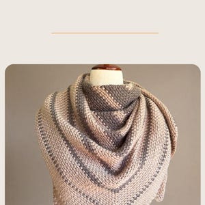 May include: A beige and gray crocheted shawl with a chevron pattern. The shawl is displayed on a mannequin and worn by a person. The image also includes the text "From Shawl to Cowl Modern Crochet Pattern."