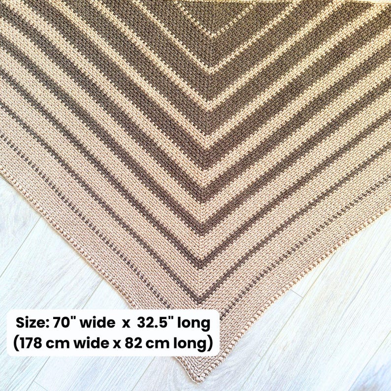May include: A handmade crochet shawl in a chevron pattern. The shawl features alternating stripes of beige and brown. The dimensions are 70 inches wide and 32.5 inches long.