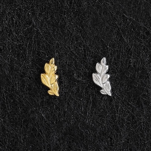 Op de afbeelding: Twee kleine oorknopjes in de vorm van delicate blaadjes. De ene oorbel heeft een heldere goudkleurige afwerking, terwijl de andere oorbel een gepolijste zilverkleurige afwerking heeft. Beide stukken tonen gedetailleerde nerven en een gebogen vorm.