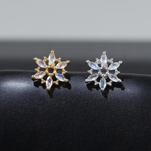 May include: Two stud earrings shaped like six-pointed stars or snowflakes. One earring is gold-toned with clear marquise-cut stones, and the other is silver-toned with clear marquise-cut stones. Each features a central circular setting.