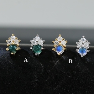 以下が含まれることがあります： 宝石のアクセントが付いたスタッドピアス4つ。2組は緑色の宝石、他の2組は青色の宝石が特徴です。各イヤリングには、メインの宝石の周りに小さな石のクラスターがあり、金または銀でセットされています。