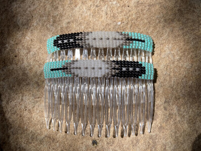 May include: Two beaded hair combs with a turquoise, white, and black feather design.